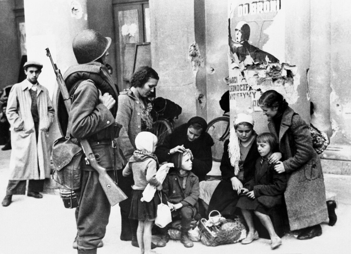 Uciekinierzy w oblężonej Warszawie Polski żołnierz i rodzina, która uciekła przed Niemcami, przy kolumnie Opery w oblężonej Warszawie. Fotografia Juliena Bryana.