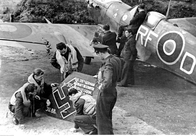 Lotnicy polskiego dywizjonu myśliwskiego 303 oglądają szczątki zestrzelonego samolotu niemieckiego "Ju 88". Z prawej widoczny samolot "Spitfire" należący do pilota Jana Zumbacha
