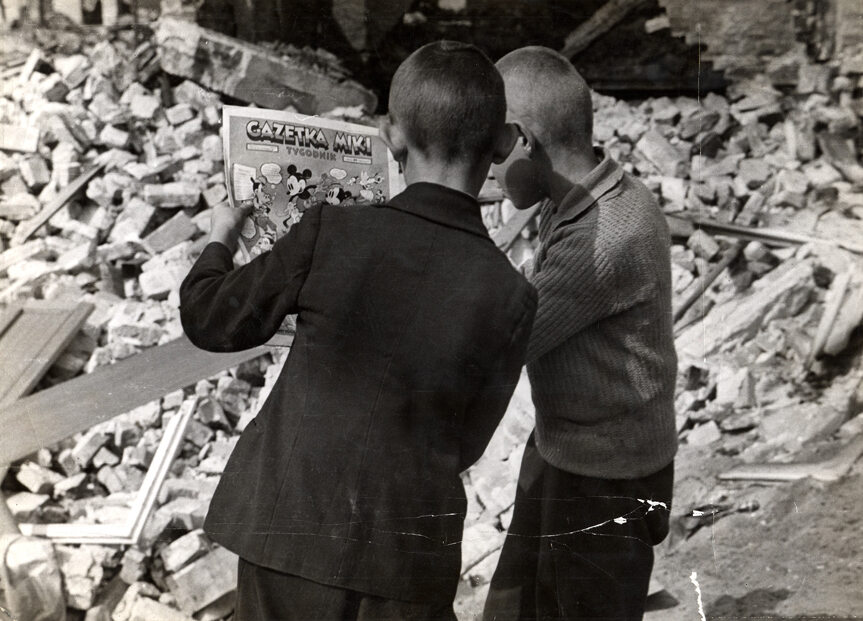 Dzieci w oblężonej Warszawie Dwóch chłopców z niedzielnym dodatkiem gazety na gruzach zburzonych budynków. Fotografia Juliena Bryana.